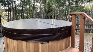A hot tub on a wooden deck with a wooden staircase leading up to it.
