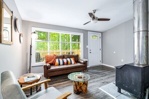 A living room with a sofa, a glass coffee table, a fireplace, and a ceiling fan.