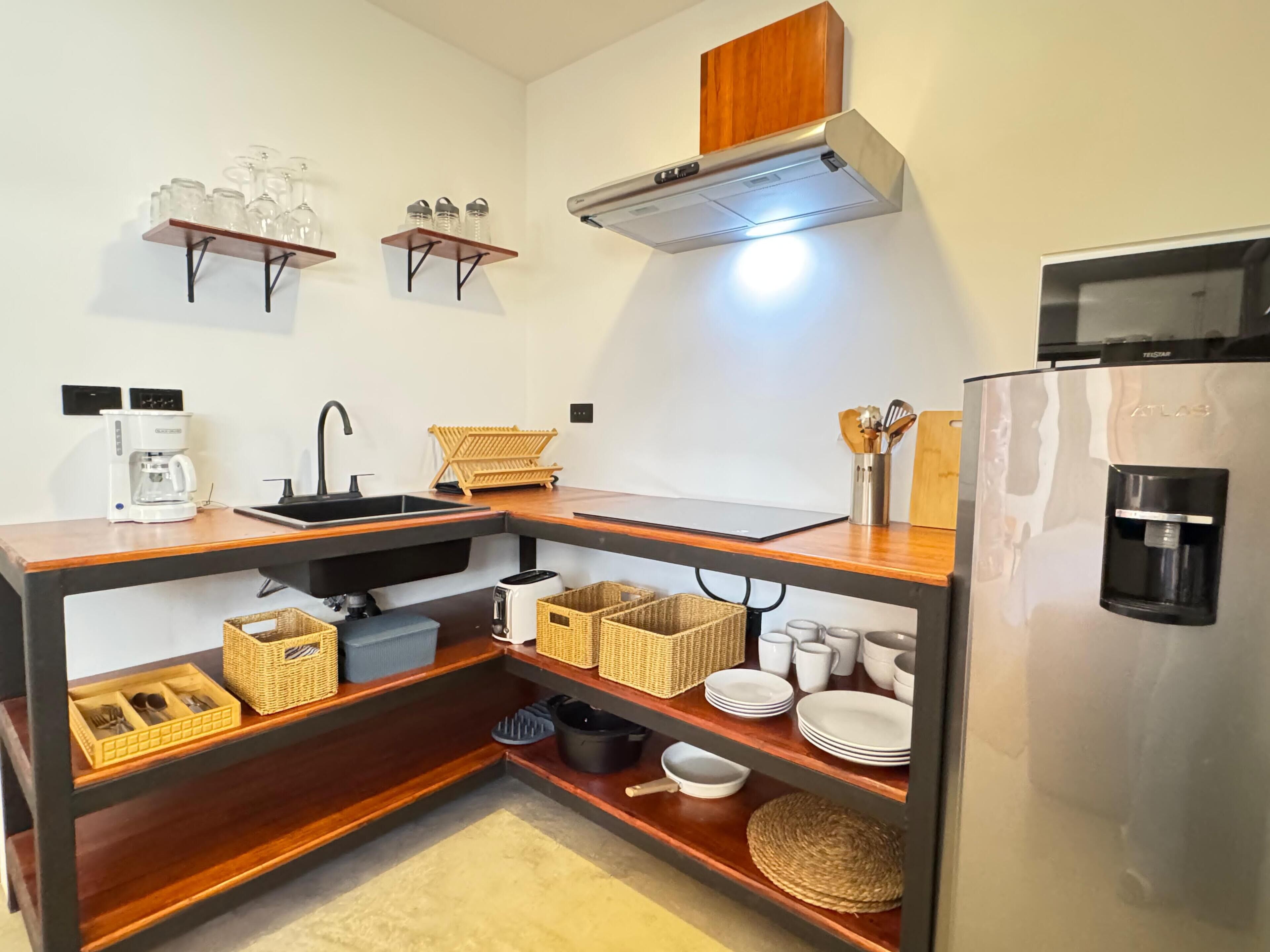 A compact kitchen with a built-in sink, a coffee maker, a toaster, and a refrigerator.