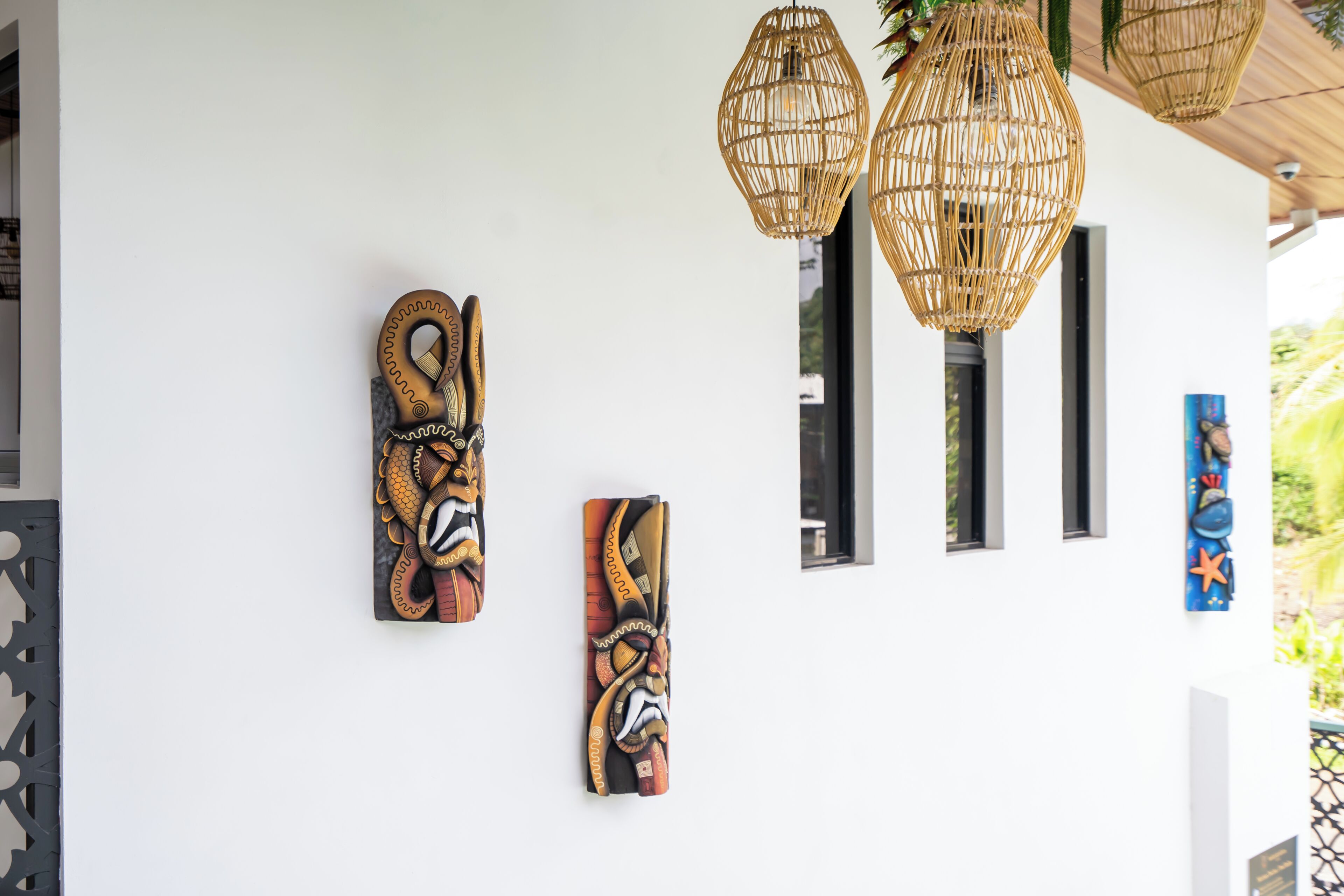A wall with three woven light fixtures and three vertical rectangular mirrors.