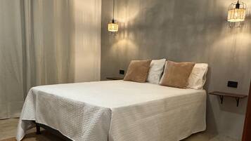 A bedroom with a large bed, two bedside tables, a rug, and two pendant lights.