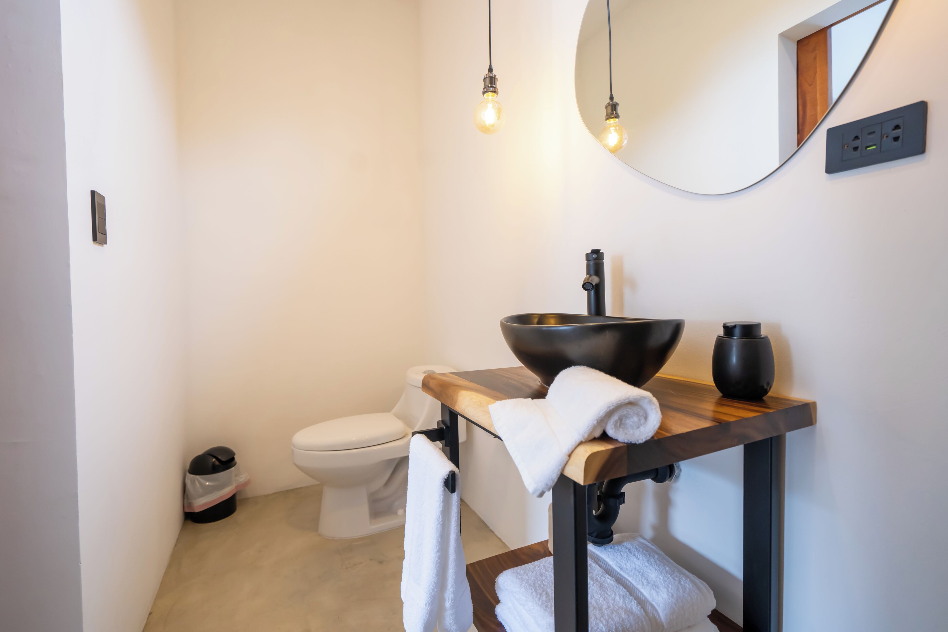 Een moderne badkamer met een houten wastafel, een grote spiegel en een wit toilet.