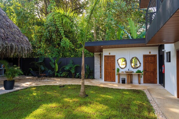 A modern building with a thatched roof, a small garden with a tree, and a wooden door.