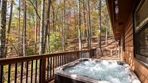 Un jacuzzi en una terraza de madera con vista a un bosque.