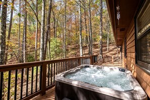 Una vasca idromassaggio su un pontile di legno con vista su una foresta.