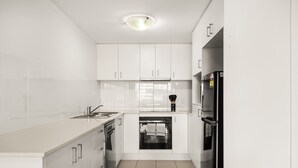 Una cocina moderna con armarios blancos, un horno negro y un refrigerador de acero inoxidable.