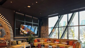 Un espace de détente moderne comprenant un ensemble de canapés, des tables rondes et un grand écran de télévision.