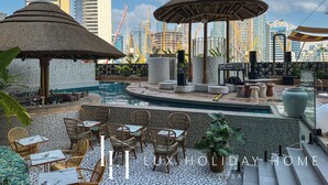 Un espace piscine aménagé sur le toit, avec des chaises longues, des parasols et une vue panoramique sur la ville.