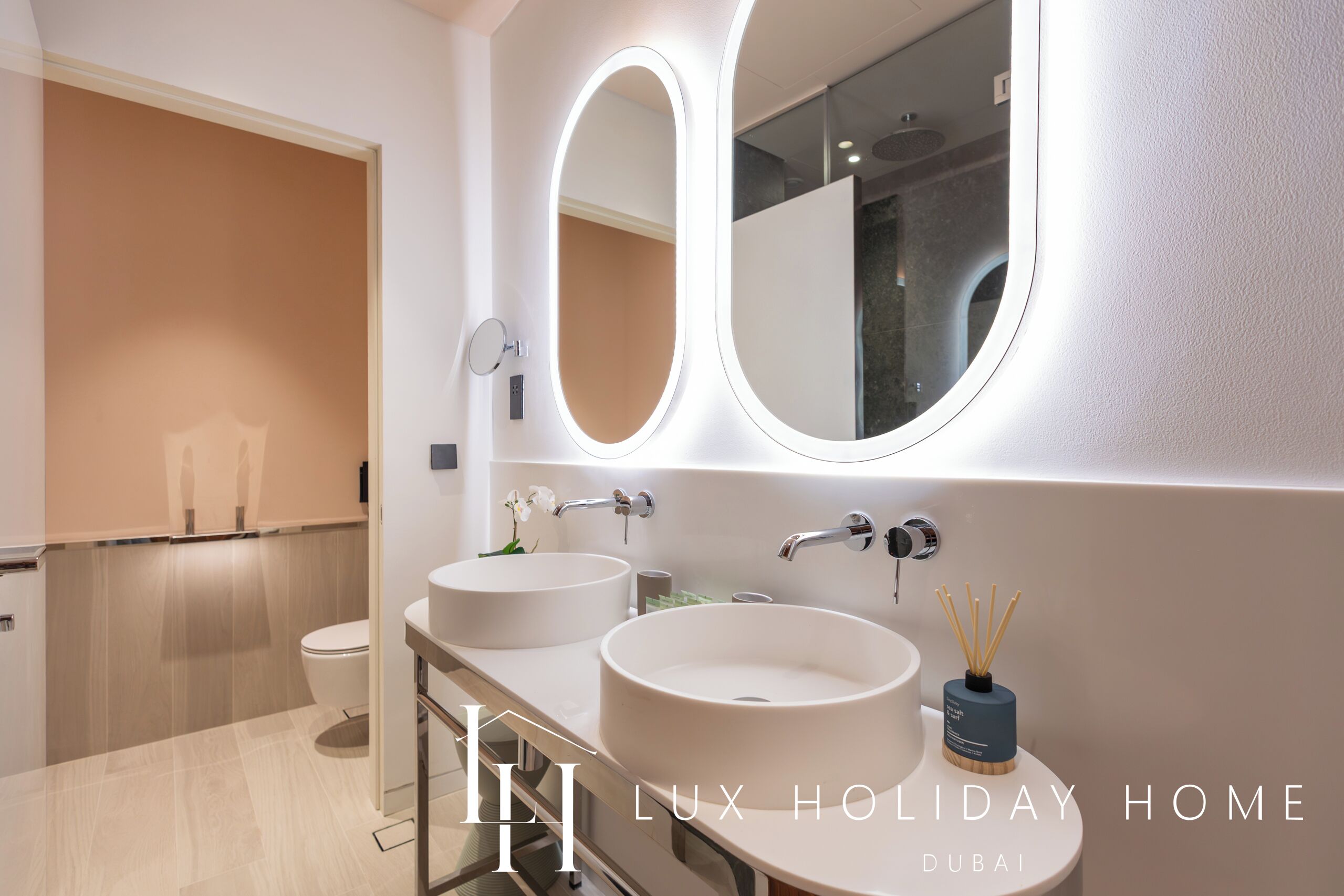 A modern bathroom with two sinks, a large mirror, and a toilet.