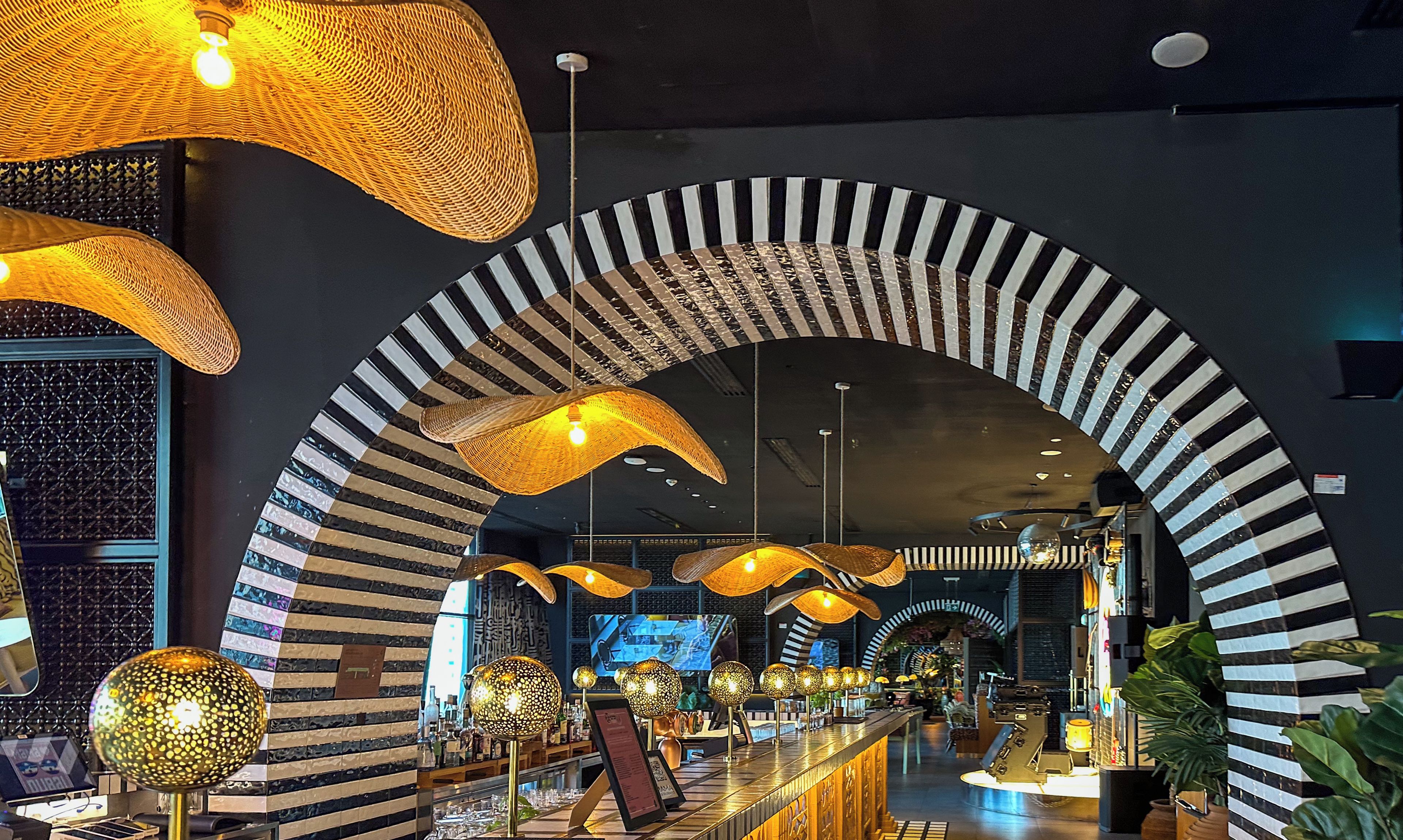 A luxurious hotel interior with distinctive black and white striped arches, a well-lit bar area, and a modern design aesthetic.