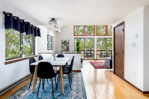 A modern interior with a dining area, large windows, and a view of the outdoors.