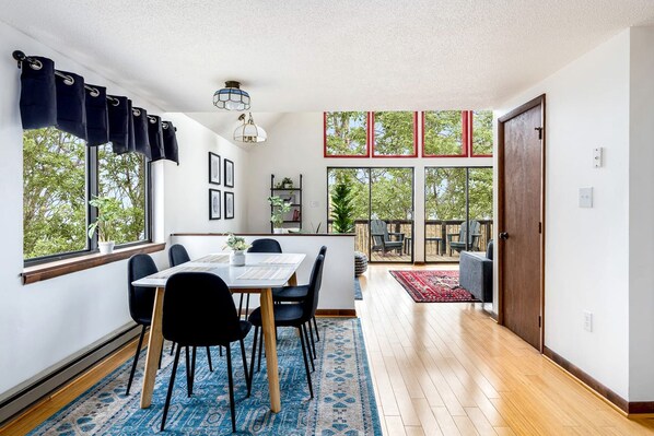 A modern interior with a dining area, large windows, and a view of the outdoors.
