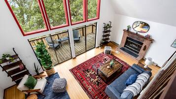 A spacious living room with a fireplace, a large window overlooking a deck, and a cozy seating area.