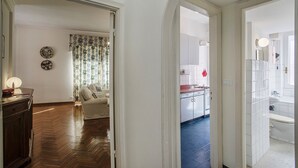 A hallway leading to a living room with a sofa and a dining area with a table and chairs. - Charming Balcony Apartment by Wonderful Italy (Santa Margherita Ligure)