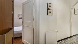 A hallway with a wooden door, a radiator, and two framed pictures on the wall. - Charming Balcony Apartment by Wonderful Italy (Santa Margherita Ligure)