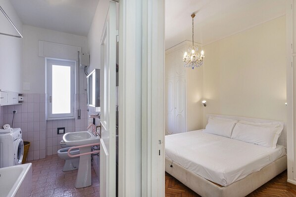 Ein Schlafzimmer mit einem Bett, einer Kandelaber und einem Fenster.