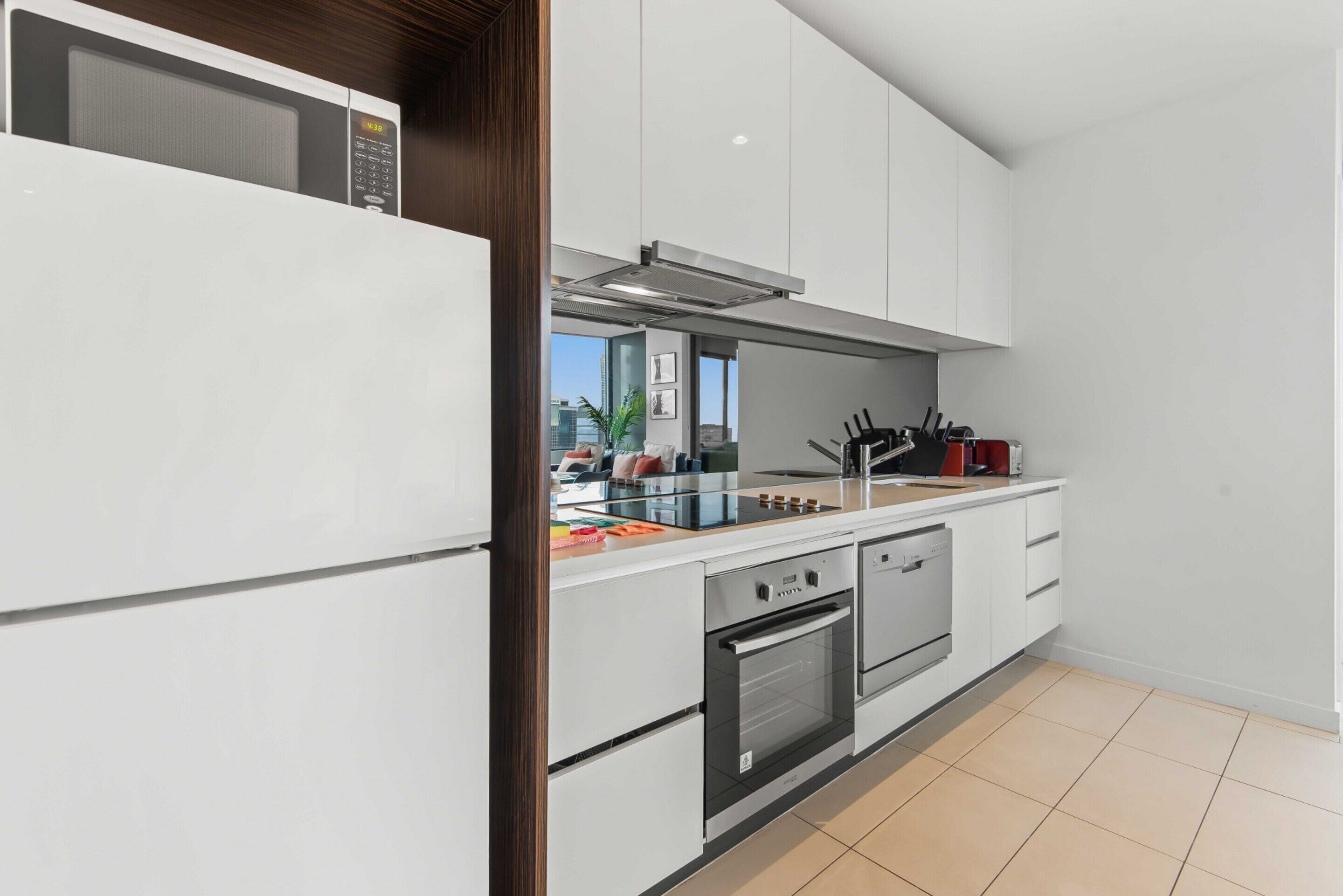 Une cuisine moderne avec des armoires blanches, un four à micro-ondes, une cuisinière et un évier.