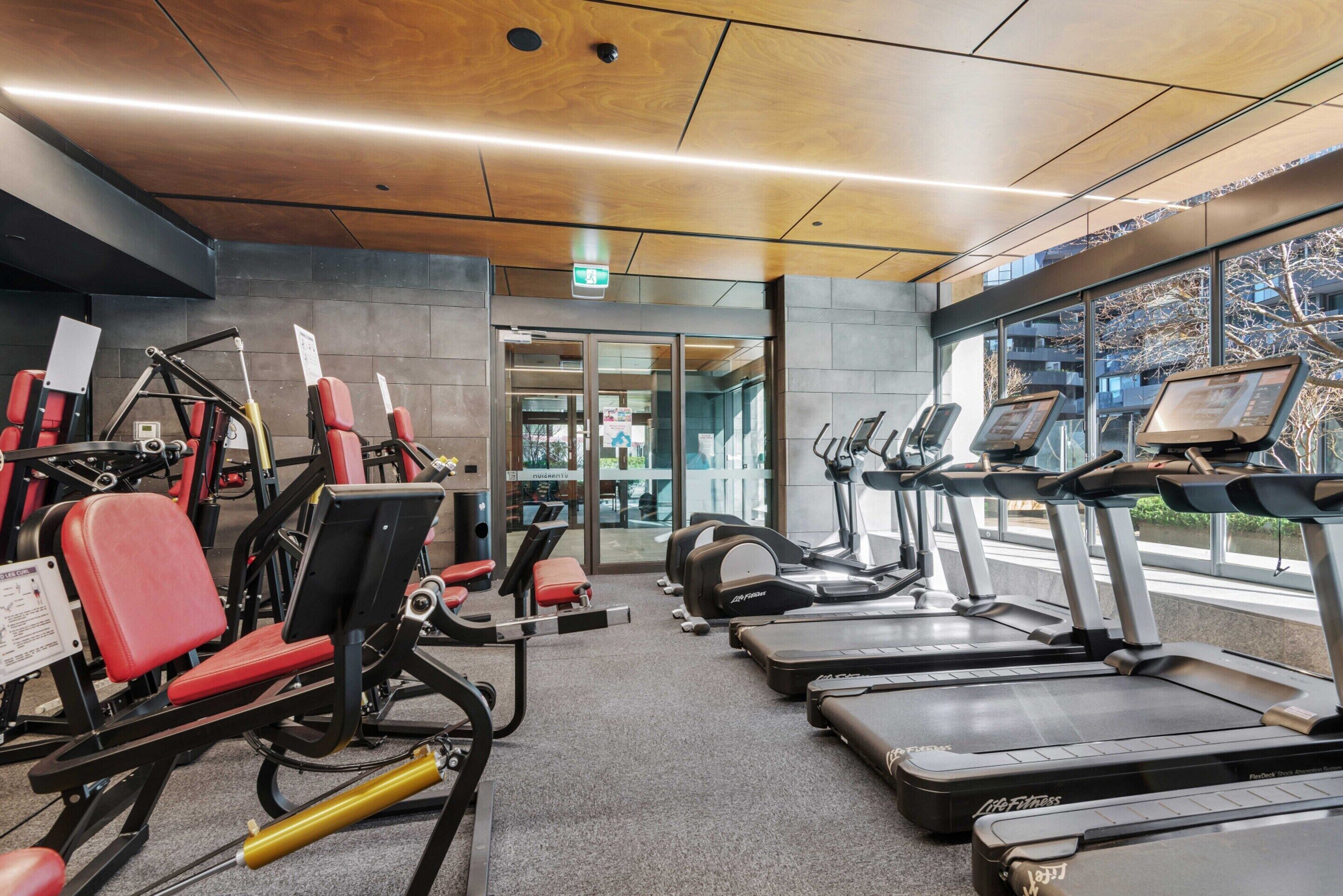 A gym with treadmills, weight machines, and exercise mats.