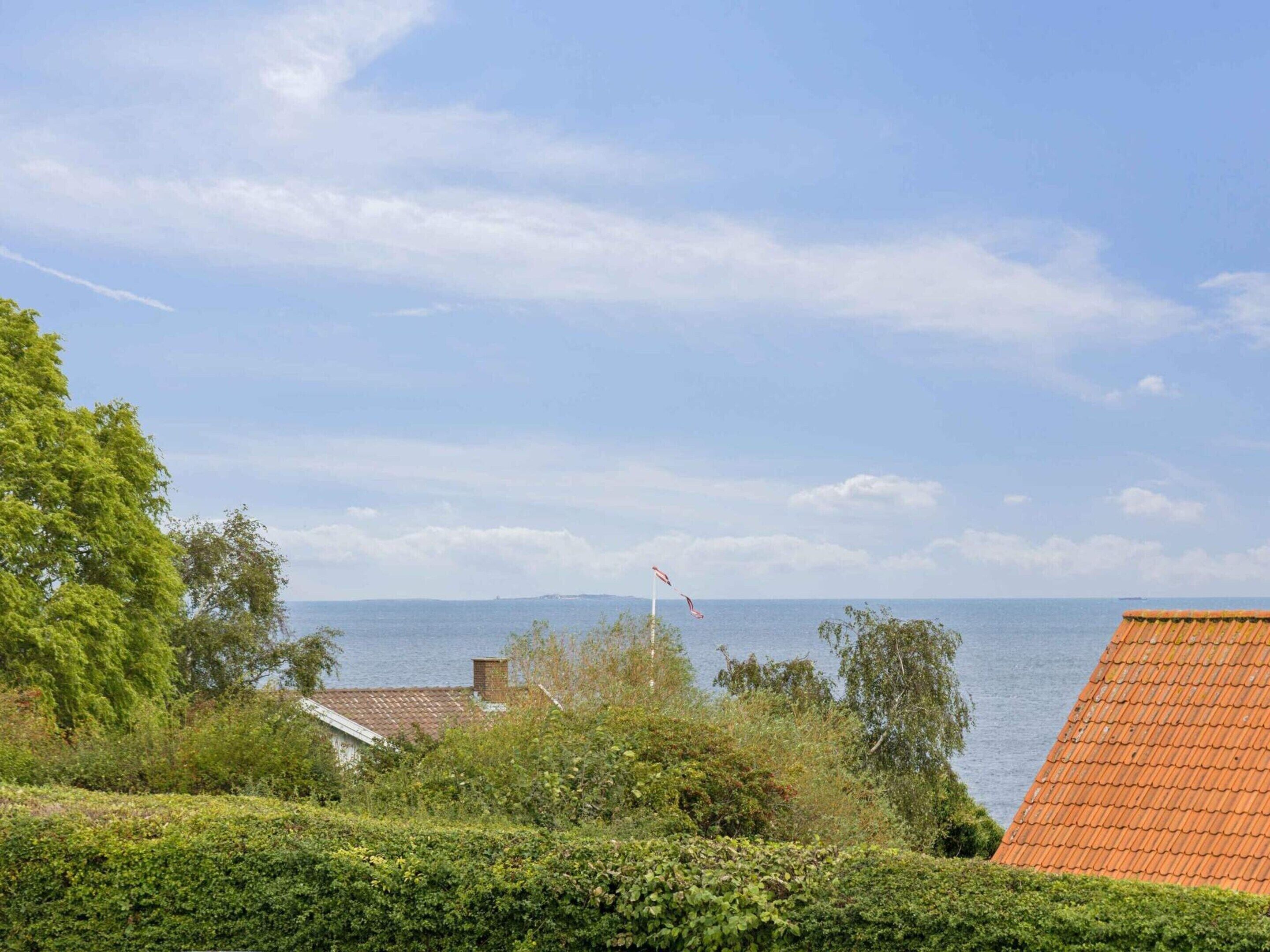 A coastal view with a clear sky, a flag, and a distant shoreline.