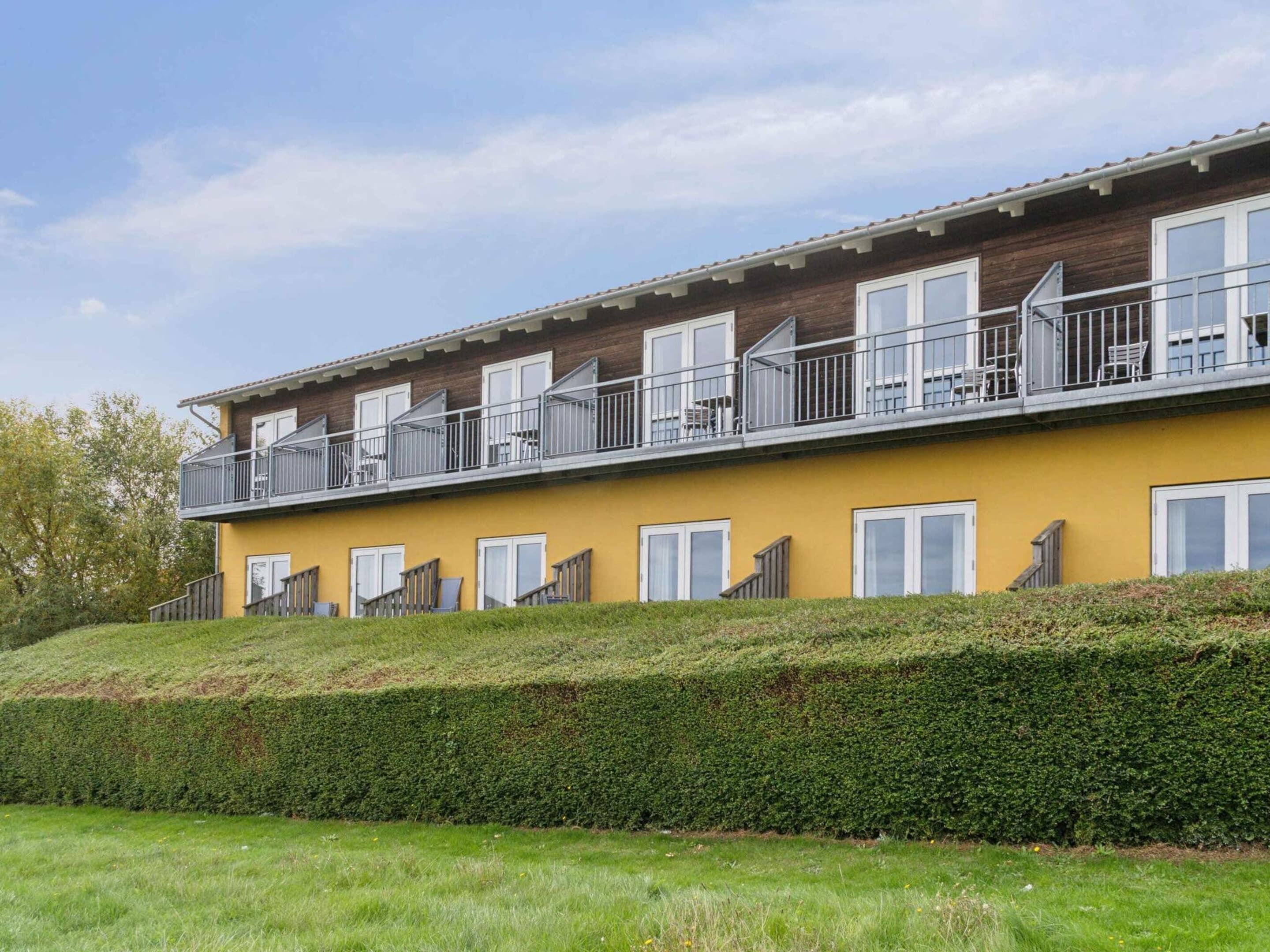 A multi-story building with balconies, wooden paneling, and a yellow facade.