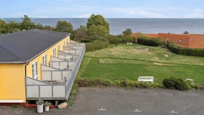 Un edificio giallo con un balcone, una zona verde e vista sul mare.