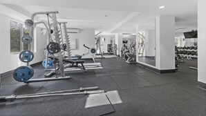 A gym with various exercise equipment, including weight machines, free weights, and cardio machines. - Stylish Brisbane City Stay With Bbq, Pool & Gym (Brisbane)