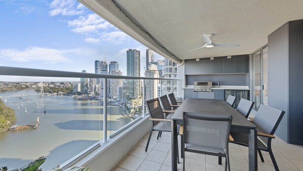 A balcony with a city view, a dining table, chairs, and a ceiling fan. - Stylish Brisbane City Stay With Bbq, Pool & Gym (Brisbane)