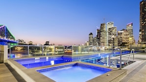 A rooftop pool with a city skyline in the background. - Stylish Brisbane City Stay With Bbq, Pool & Gym (Brisbane)