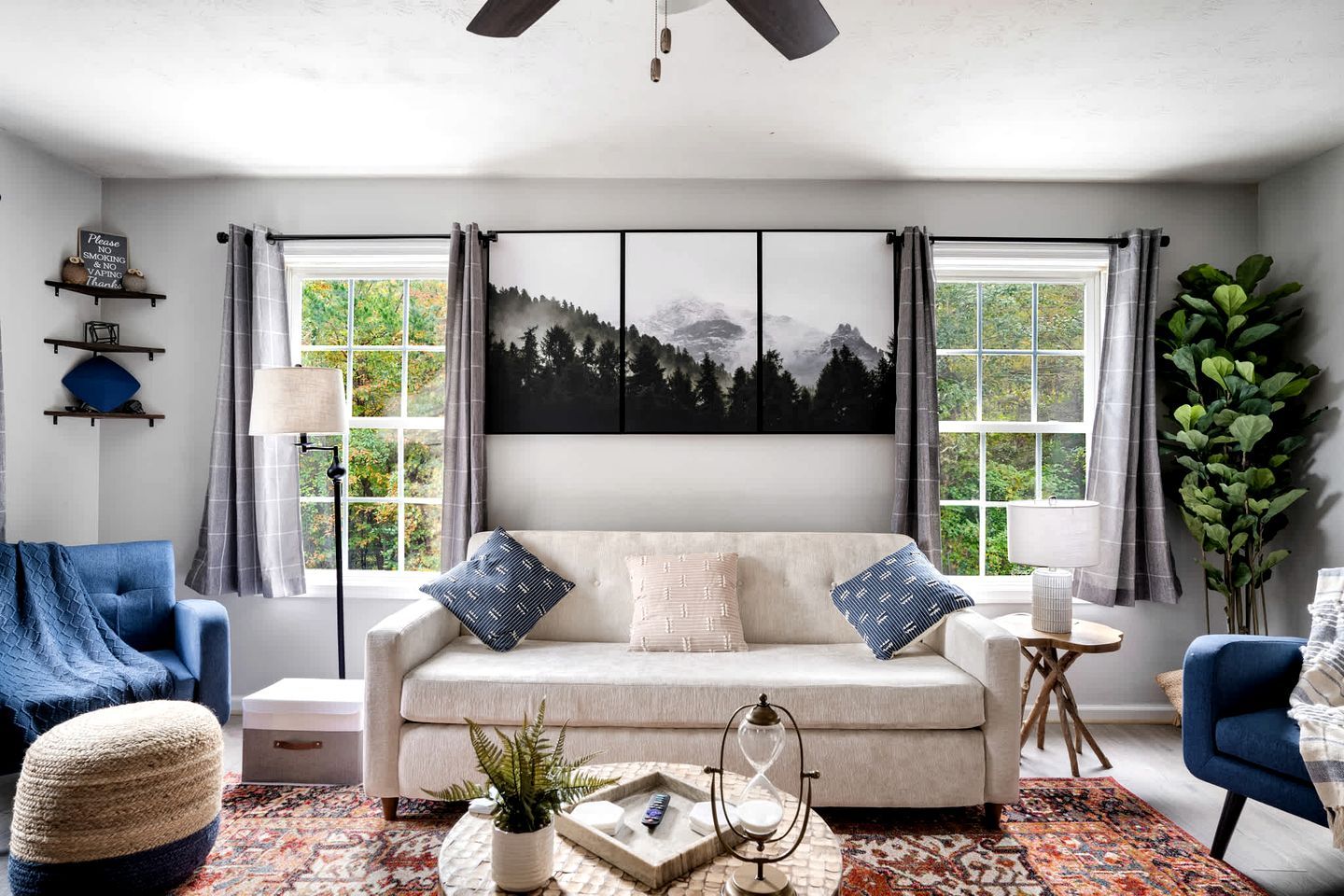 A living room with a sofa, two armchairs, a coffee table, a lamp, a plant, and a painting on the wall.