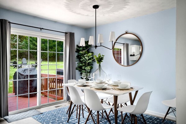 A dining area with a table set for four, a large mirror, and a view of the outdoors.