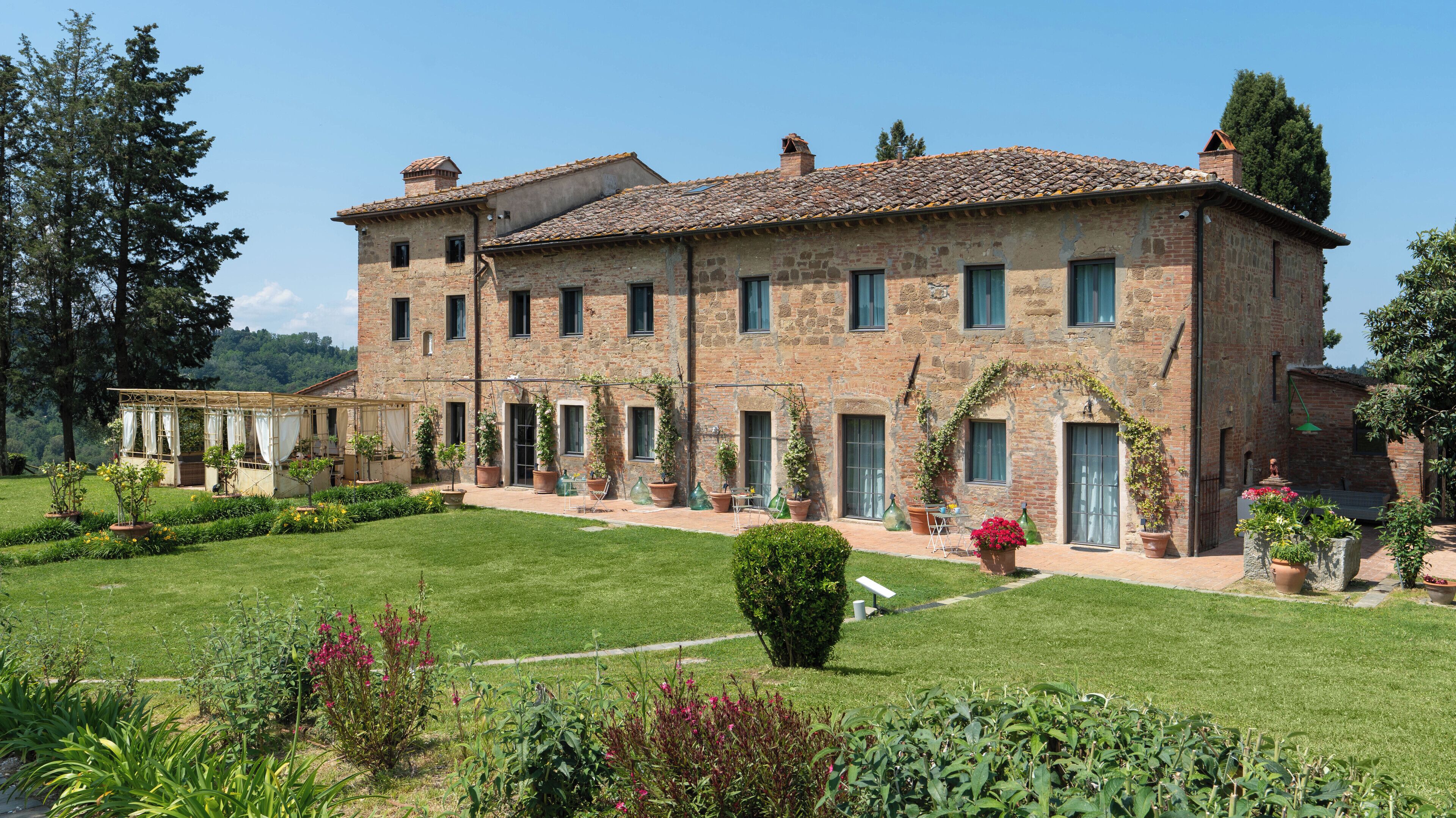 A large stone building with multiple windows and a well-maintained garden.
