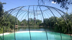 A pool with a metal structure overhead, surrounded by trees and a clear sky. - Glamping Retreat in Texas in this Wonderful Bell Tent Rental in Spicewood (Spicewood)