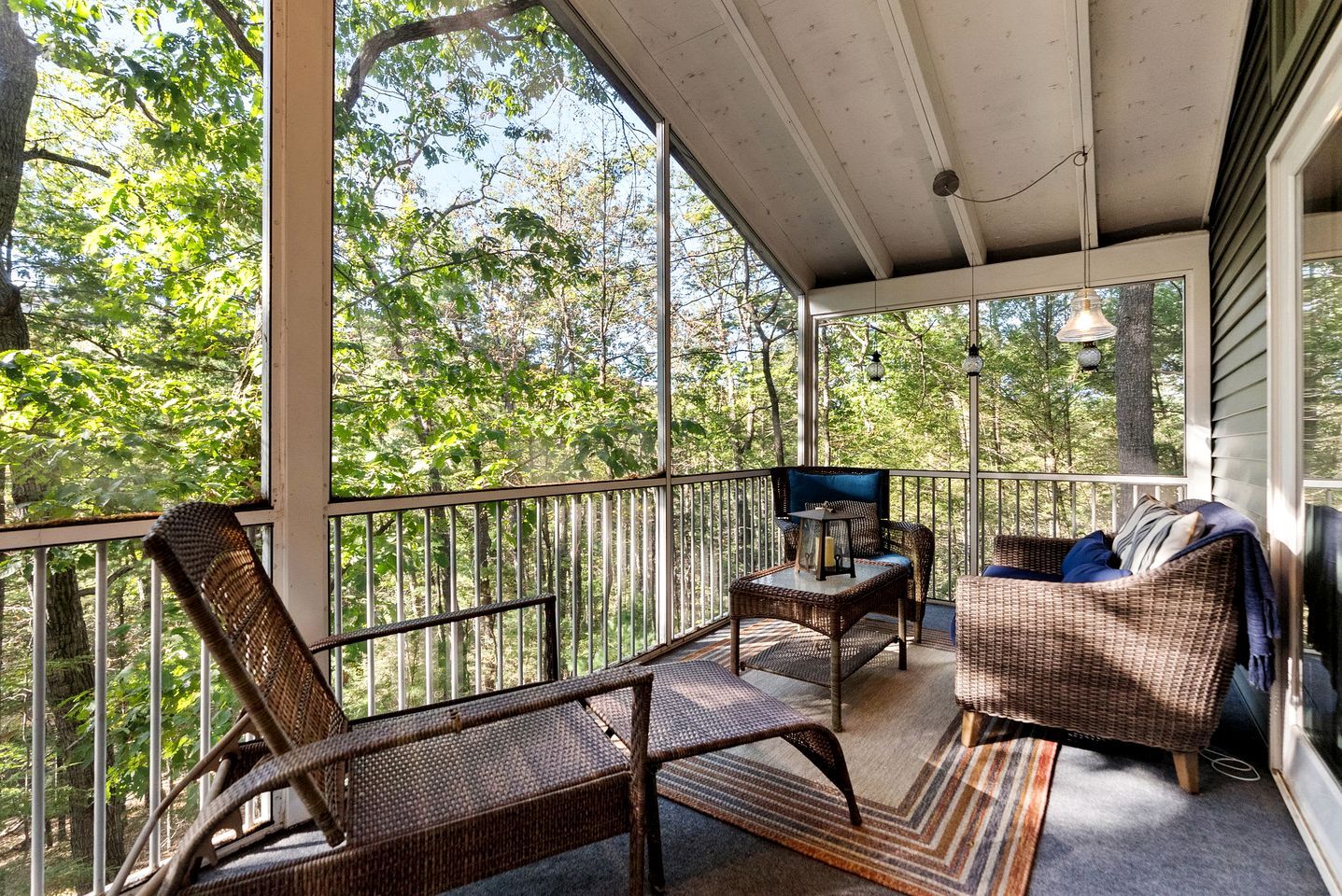 A covered porch with wicker furniture, a table, and a television.