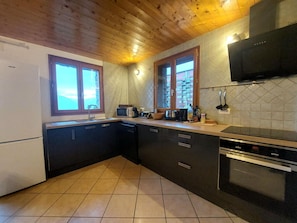 A compact kitchen with dark cabinets, a microwave, a stove, and a window with a view of buildings.