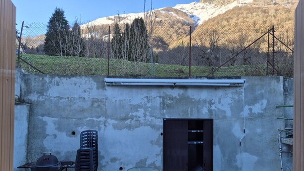 A fenced outdoor patio with a grill, a table, and a door leading to a building. - 68 sqm 3-Bedroom Apartment with Terrace and Ski Locker (Cauterets)