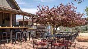 An outdoor patio with a grill, bar stools, and tables. - Safari Tent Adventure in Kanab, Utah: A Unique Glamping Experience (Kanab)