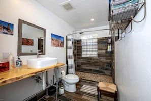 Un baño con lavamanos blanco, espejo, ducha e inodoro.