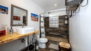 A bathroom with a white sink, mirror, shower, and toilet. - Safari Tent Adventure in Kanab, Utah: A Unique Glamping Experience (Kanab)