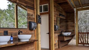 Una cabaña de madera con baño que incluye dos lavamanos, un espejo y una puerta.