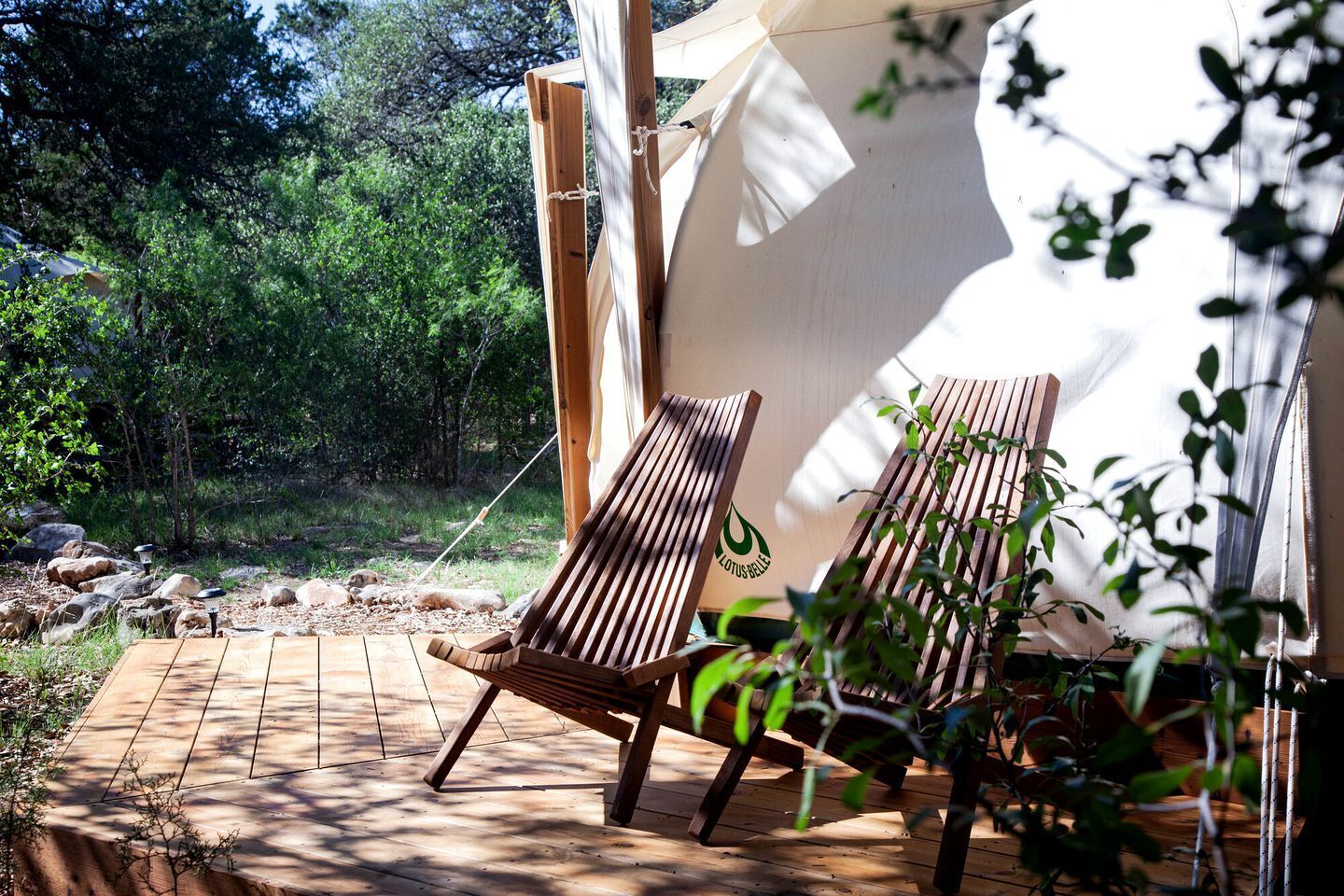 Une terrasse en bois avec deux chaises longues, une tente et un cadre extérieur naturel.