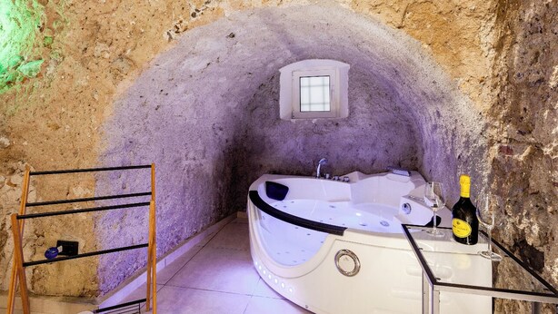 A spa room with a bathtub, a small window, and a bottle of champagne. - Antrum Loft, eaperience with Jacuzzi (Salerno)