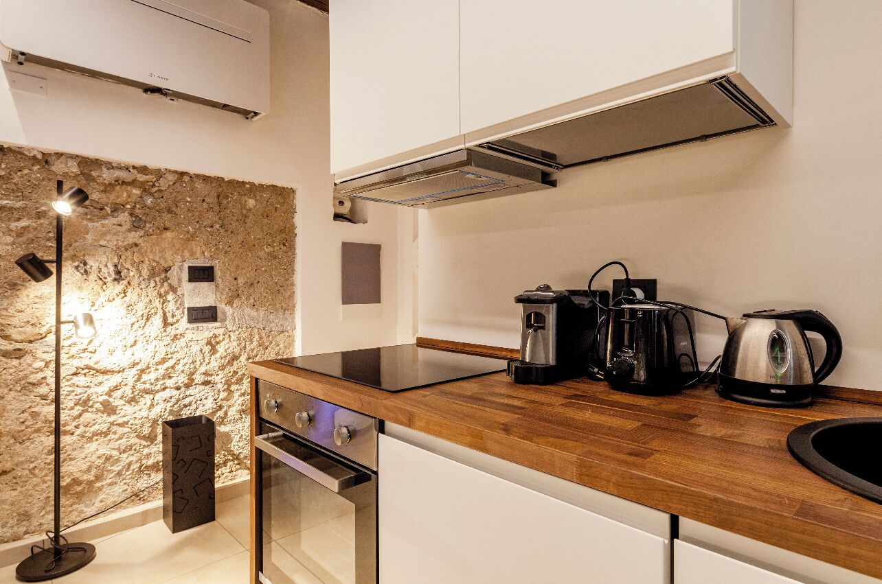 Une cuisine moderne avec un mur en pierre, un four encastré et des appareils électroménagers en acier inoxydable.