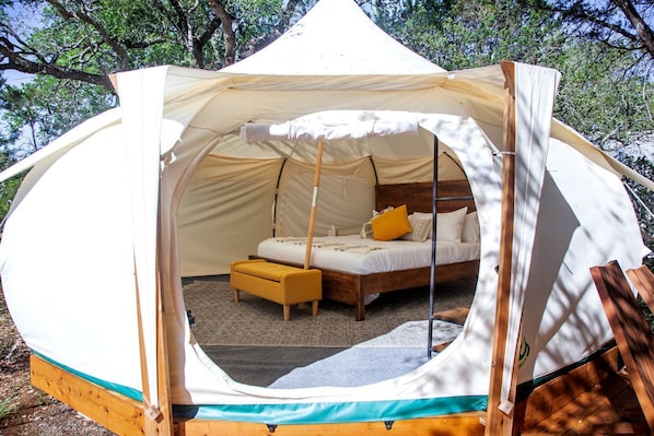 A dome-shaped tent with a bed, a bench, and a small table.