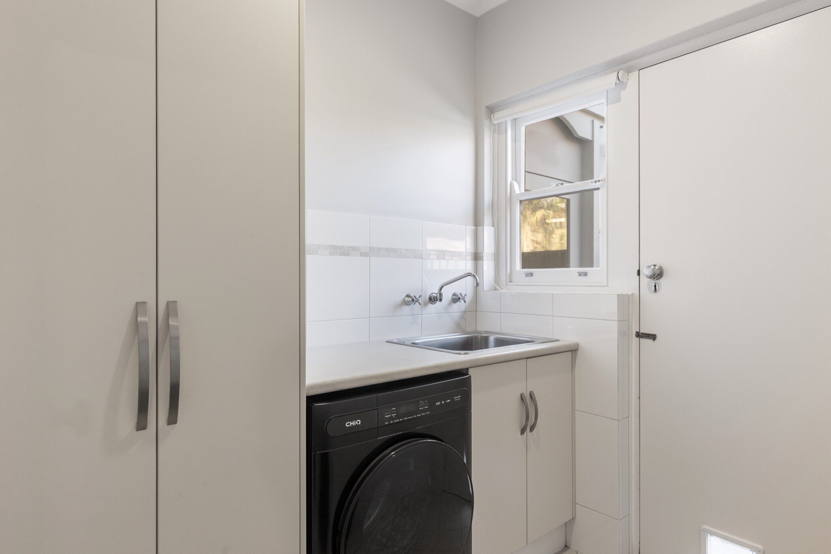 A compact kitchen with a dishwasher, a sink, and a window above the sink.