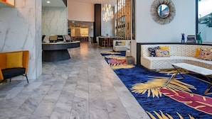 A modern lobby with a reception desk, seating area, and a large mirror. - 2-bed Beach Apartment With Pool, Parking & Balcony (Gold Coast)