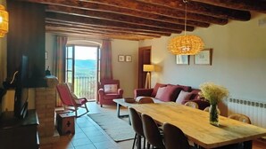 A cozy living room with a fireplace, a dining table, and a sofa. - Casa Serra de Dalt (Lladurs)