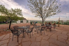 Eine Terrasse im Freien mit Tischen und Stühlen, umgeben von Bäumen und Blick auf die Landschaft.