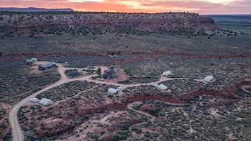 An aerial view of a desert landscape with a road, several buildings, and sparse vegetation.