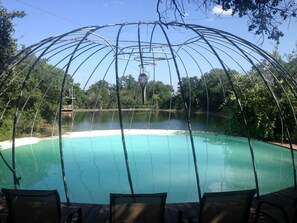 A pool with a metal structure overhead, surrounded by trees and a clear sky. - Romantic Getaways in Fully-Equipped Tree House Rental in Spicewood, Texas (Spicewood)