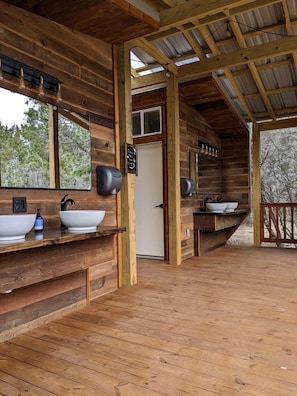 A wooden cabin with a bathroom featuring two sinks, a mirror, and a door.